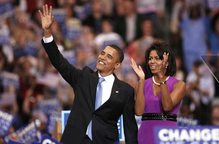 U.S. Democratic presidential candidate Senator Barack Obama (D-IL) waves to the audience as his wife Michelle (R) claps, at his South Dakota and Montana presidential primary election night rally in St. Paul, Minnesota June 3, 2008.  