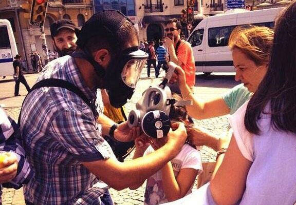 A man helps a girl put on a gas mask to protect herself from the tear gas